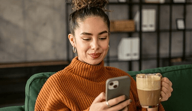 Person checking their phone while holding a mug